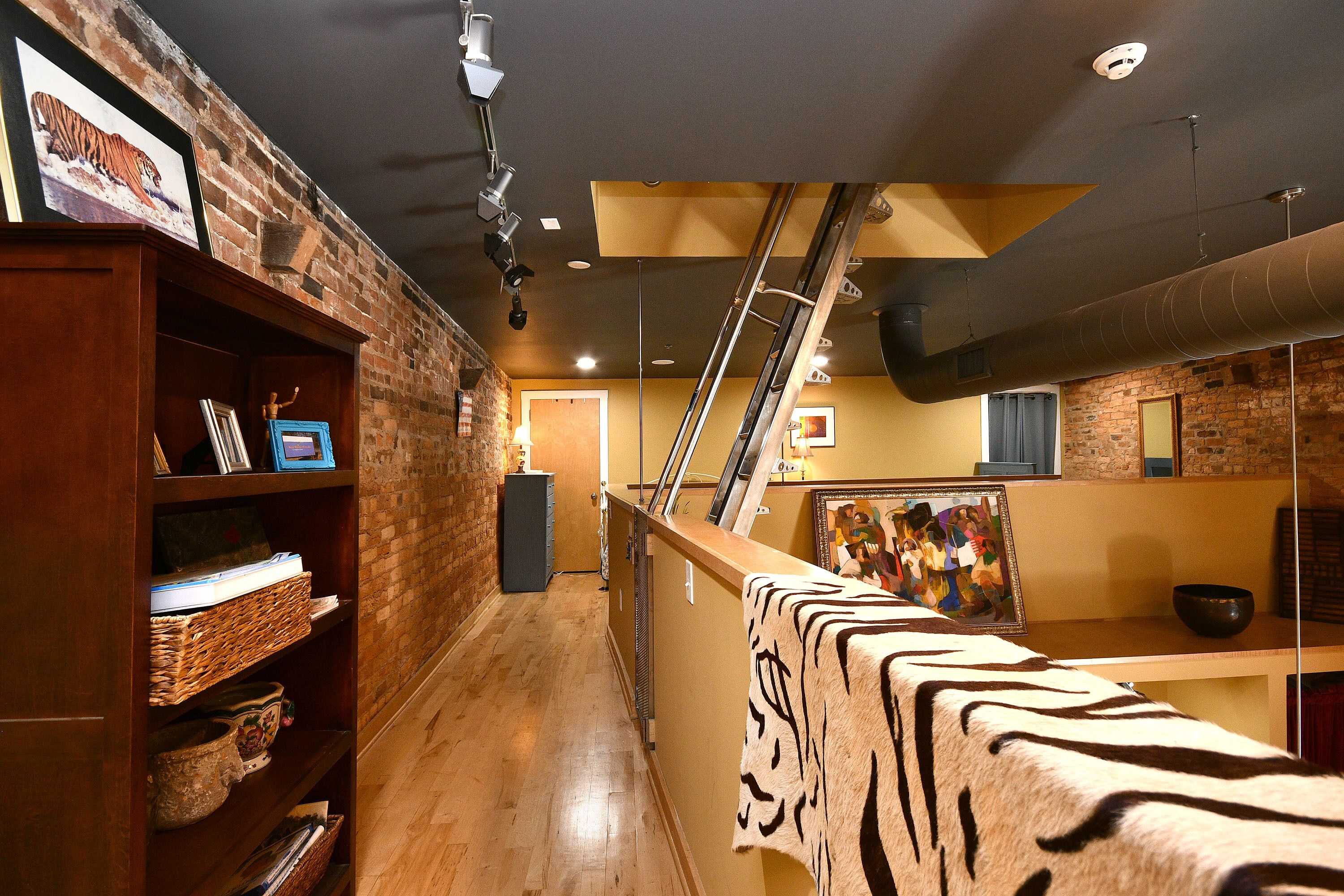 A hallway with a brick wall, wooden shelves, and a zebra-patterned rug.