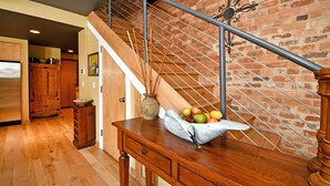 A wooden staircase with a metal railing, a vase with a plant, and a bowl of fruit on a wooden table. - Luxury Loft and Rooftop NOMA Square, Sleeps 8-10 (Greenville)