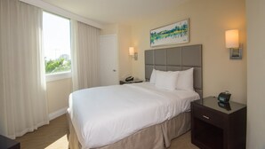 Ein Hotelzimmer mit einem großen Bett, einem Nachttisch, einer Lampe und einem Bild an der Wand.