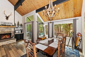 Ein rustikales Interieur mit Kamin aus Stein, Esstisch aus Holz und einer Kristallleuchtre.