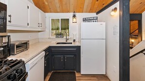 A compact kitchen with a stove, oven, and refrigerator, a window with a view, and a sign on the refrigerator. - Steps from Snow Summit Resort! Ski-In Ski-Out! Wifi & Cable! (Big Bear Lake)