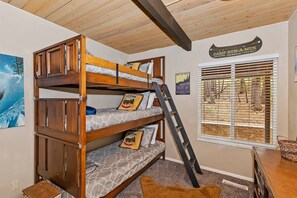 A bunk bed with a ladder, a window with blinds, and a wall sign.