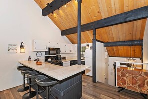 Eine moderne Küche mit Bar, Holzbalkendecke und einem Schrank mit Steinmuster.