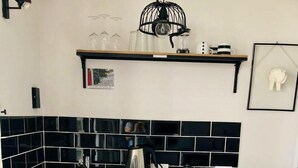 A modern kitchen with a black tiled backsplash, a stainless steel sink, and a built-in dishwasher. - My Shadows – Elegant Stay Close to Eagle Beach (Oranjestad)