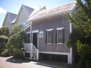 A two-story house with a front porch, a staircase, and a small garden area.