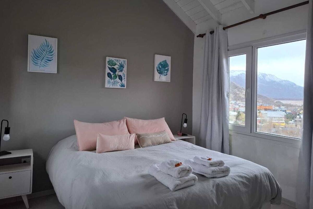 Une chambre avec un grand lit, deux tables de chevet et une fenêtre donnant sur la montagne.