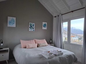 Un dormitorio con una cama grande, dos mesitas de noche y una ventana con vistas a la montaña.