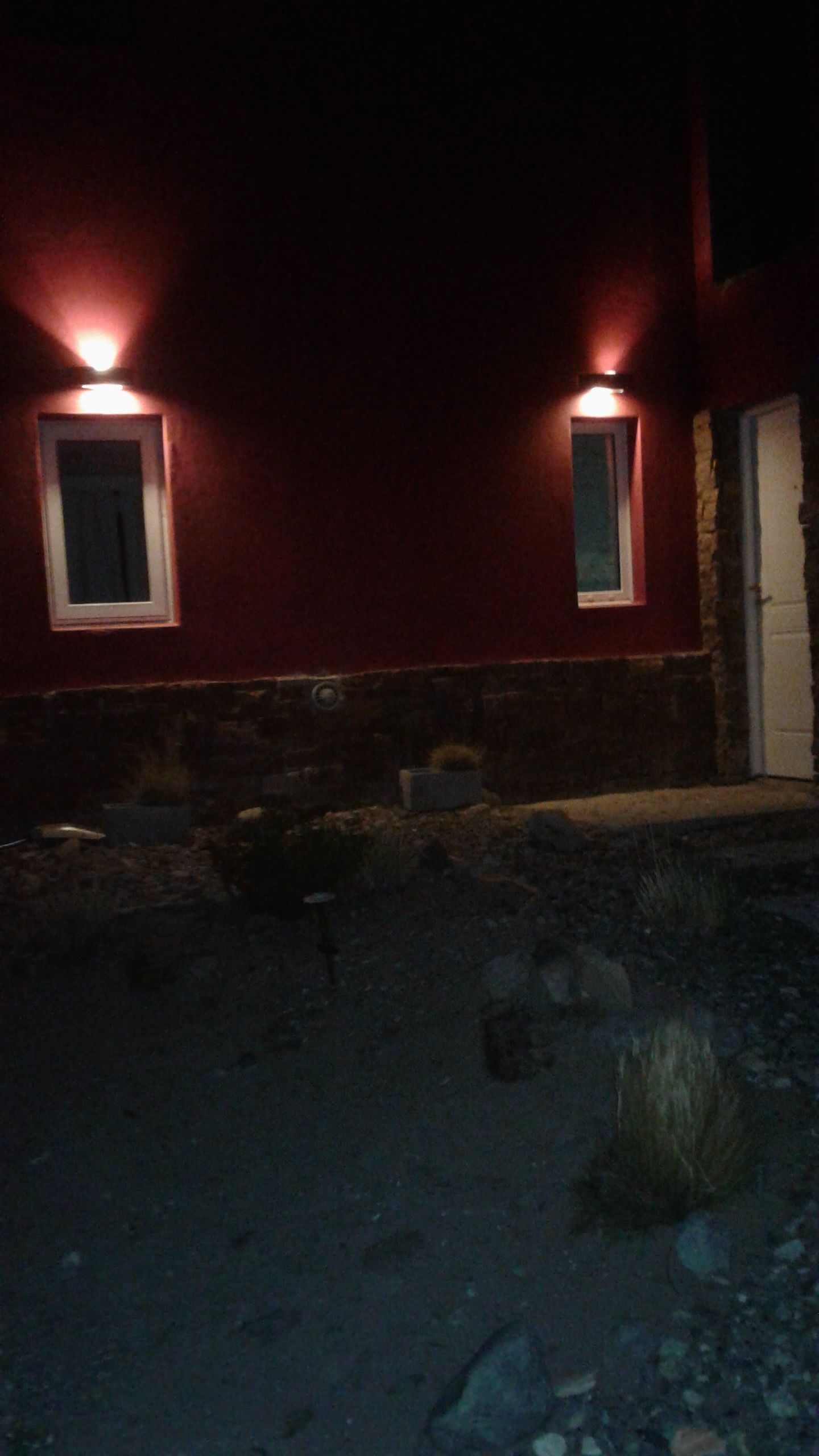 Un edificio con dos ventanas iluminadas y un cimiento de piedra.