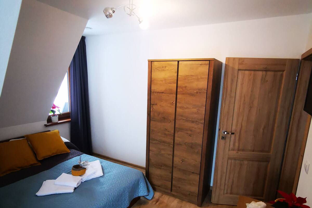 A bedroom with a bed, a wardrobe, and a bedside table with a vase of flowers.