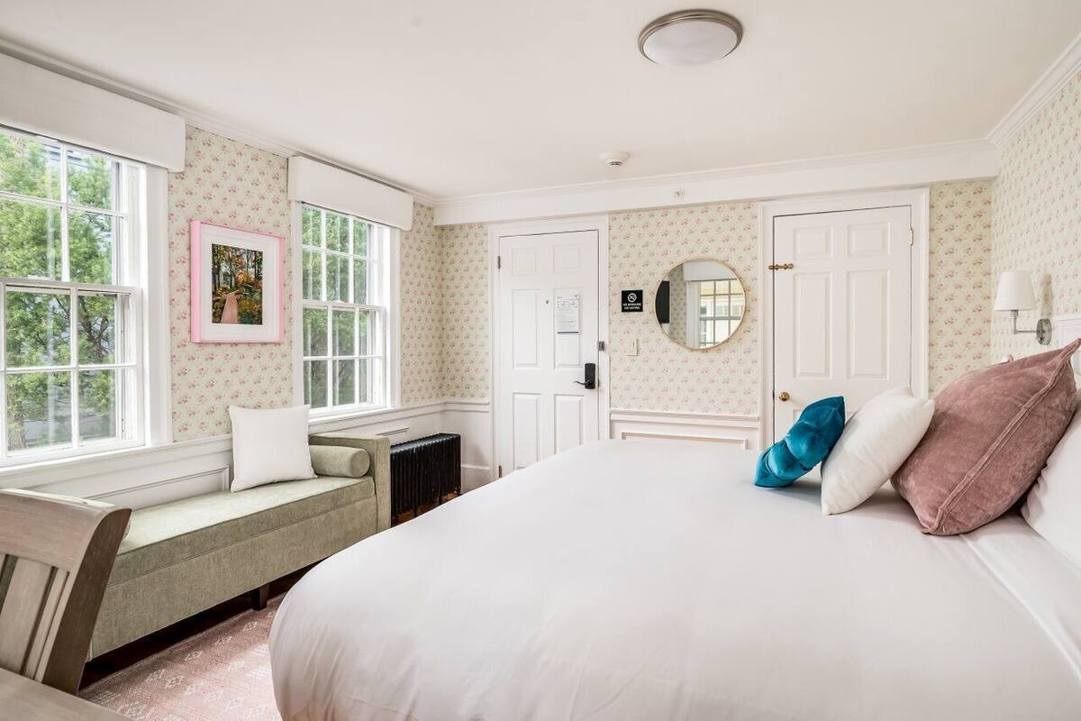 A bedroom with a large bed, a window seat, and a radiator.