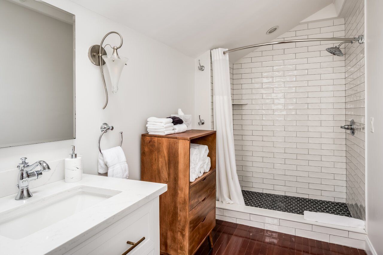A modern bathroom with a white sink, wooden vanity, and a glass shower enclosure.
