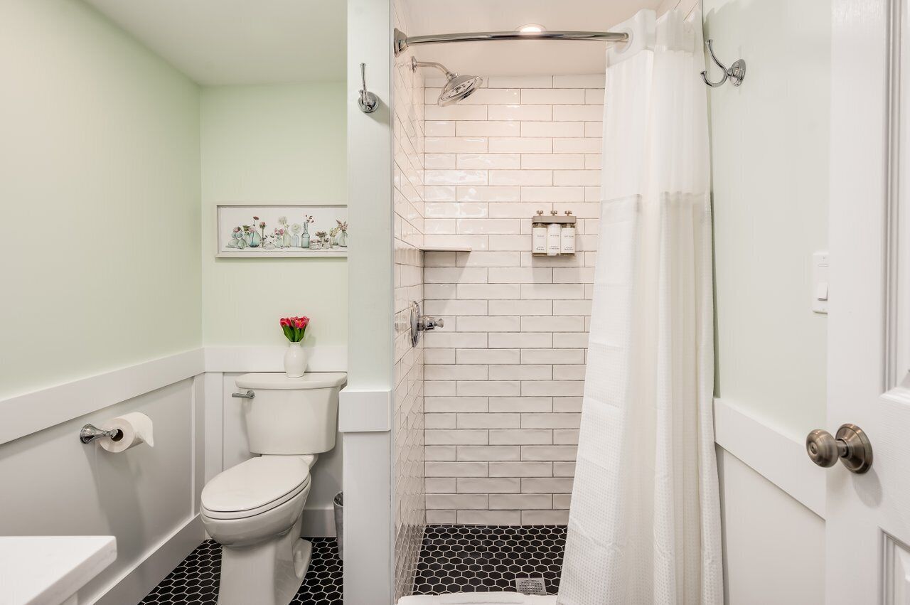 A bathroom with a toilet, a shower with a glass door, and a sink.