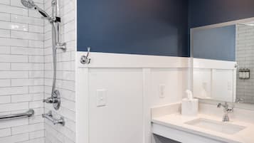 A modern bathroom with a shower, a sink, and a mirror.