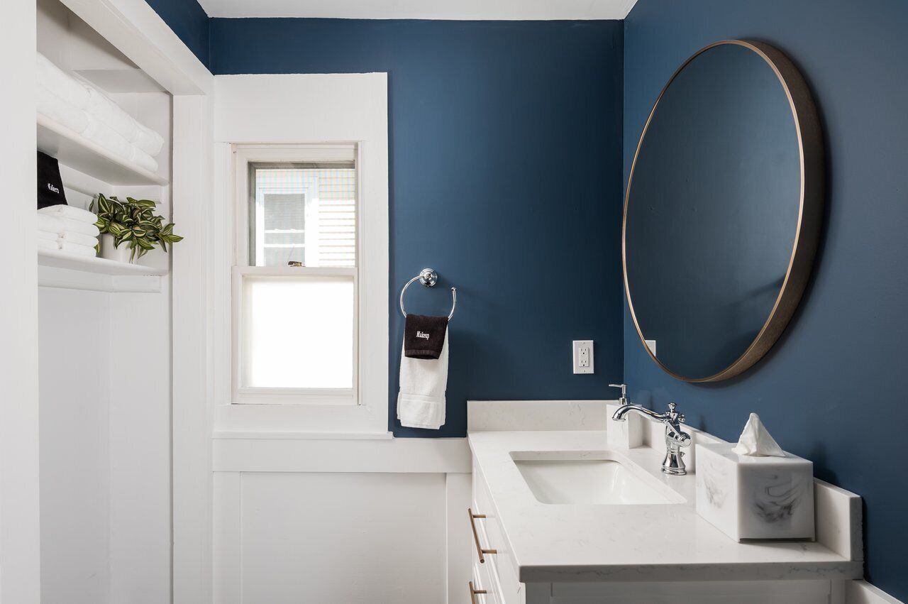 A bathroom with a white vanity, a large mirror, and a window.