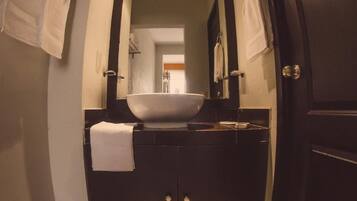 Un baño con tocador oscuro, un espejo grande y un lavabo blanco.