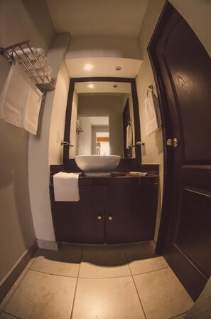 A bathroom with a dark vanity, a large mirror, and a white sink. - Hotel Belisario INN (Guadalajara)