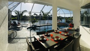 A dining area with a view of a pool and palm trees.