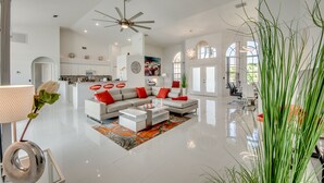 A spacious living room with a modern sofa set, a dining area, and a kitchen in the background.