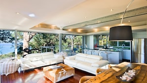 Un salon moderne avec un canapé blanc, une table basse en bois et une vue sur l’extérieur.