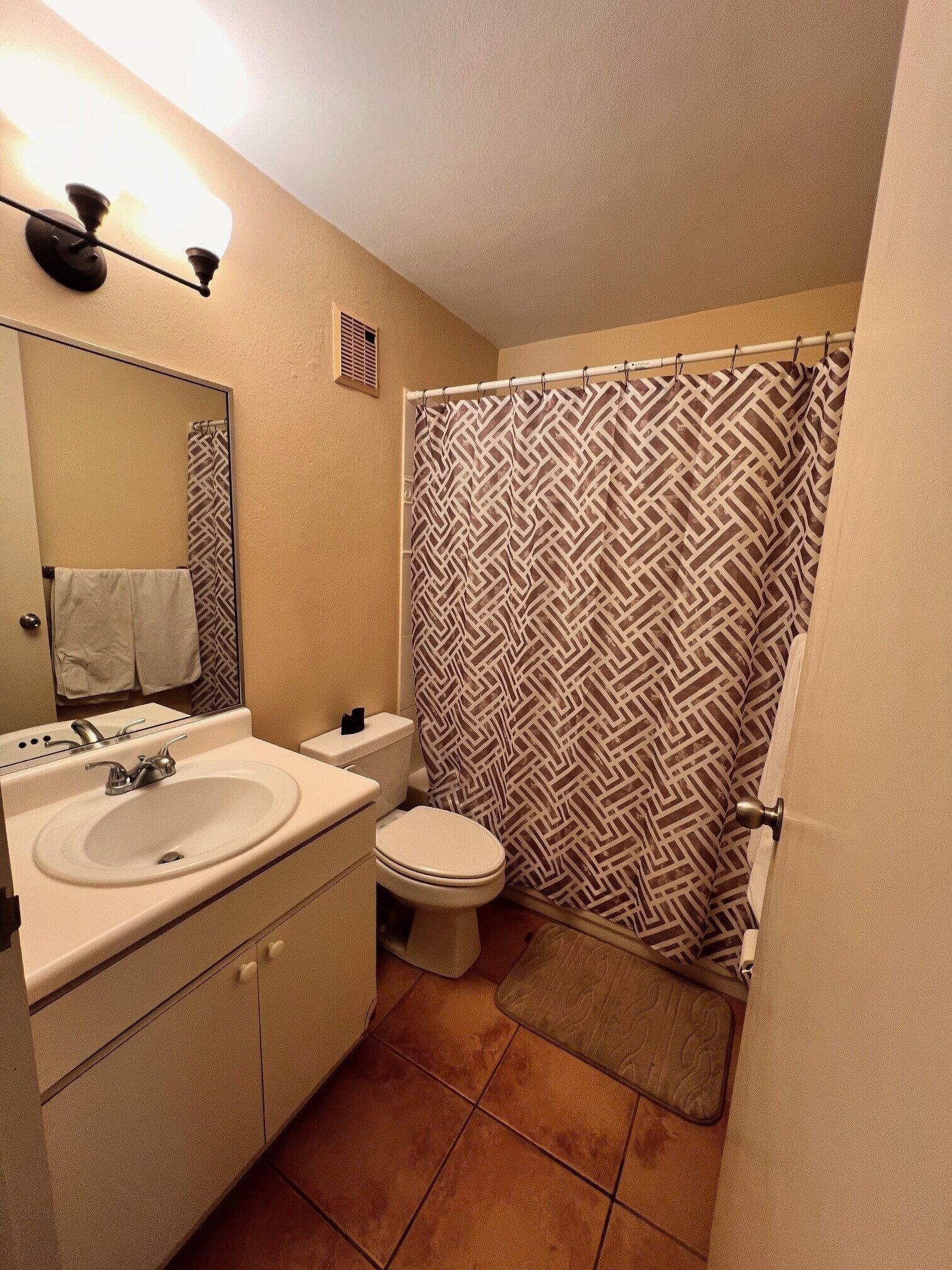 A bathroom with a sink, toilet, and shower curtain.