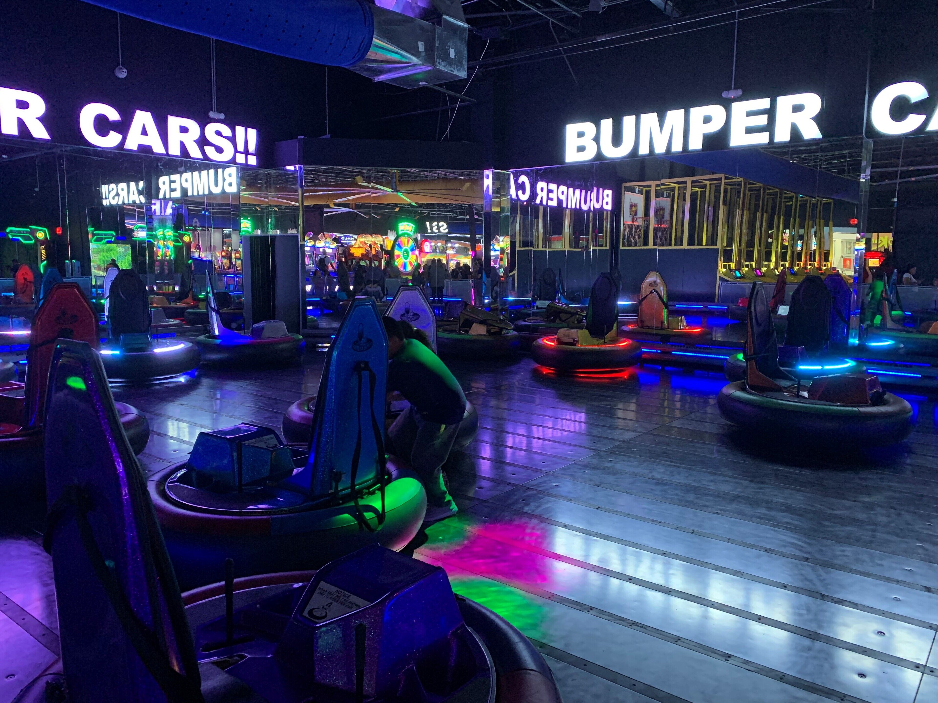 An indoor amusement area with bumper cars and neon signs.