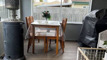 Eine überdachte Terrasse mit Tisch und Stühlen, einem Heizstrahler und Blick ins Freie.