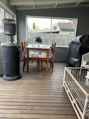 A covered patio with a table and chairs, a heater, and a view of the outside. - Fairway Views Accomadation (Warragul)
