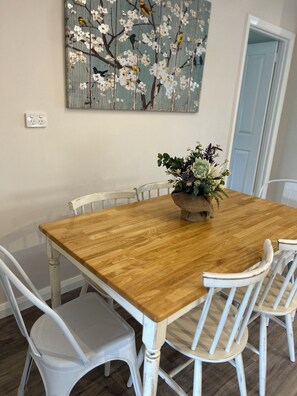 A dining area with a wooden table, white chairs, and a floral centerpiece.