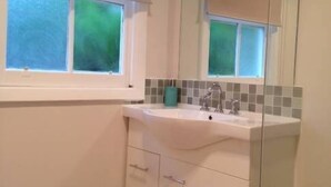 A bathroom with a window, a sink, and a mirror. - Fairway Views Accomadation (Warragul)
