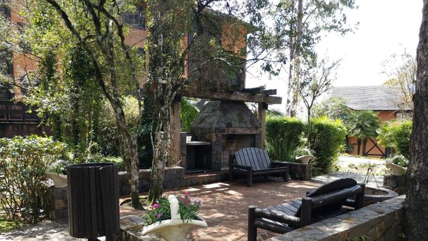 Un área de fogata de piedra con asientos, rodeada de follaje y un muro de piedra.