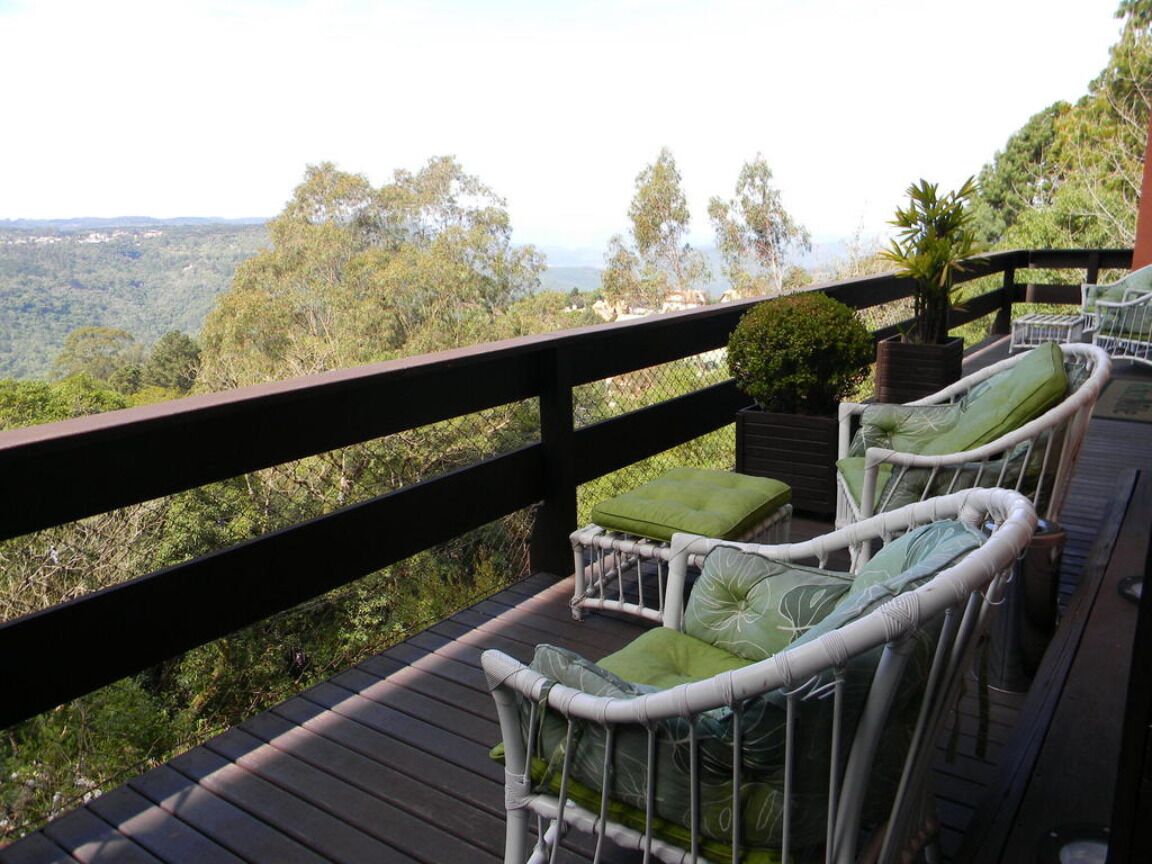 Une terrasse dotée de chaises en osier et offrant une vue sur un paysage boisé.