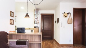 Un espacio habitable compacto con kitchenette, un sofá, una mesa de comedor y piso de madera.