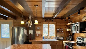 Una cucina in stile baita con isola centrale, mobili in legno, frigorifero in acciaio inossidabile, forno a microonde e piano cottura.
