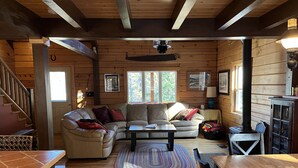 Un accogliente interno di una baita con pavimento in legno, un divano, un tavolino da caffè e un tavolo da pranzo.