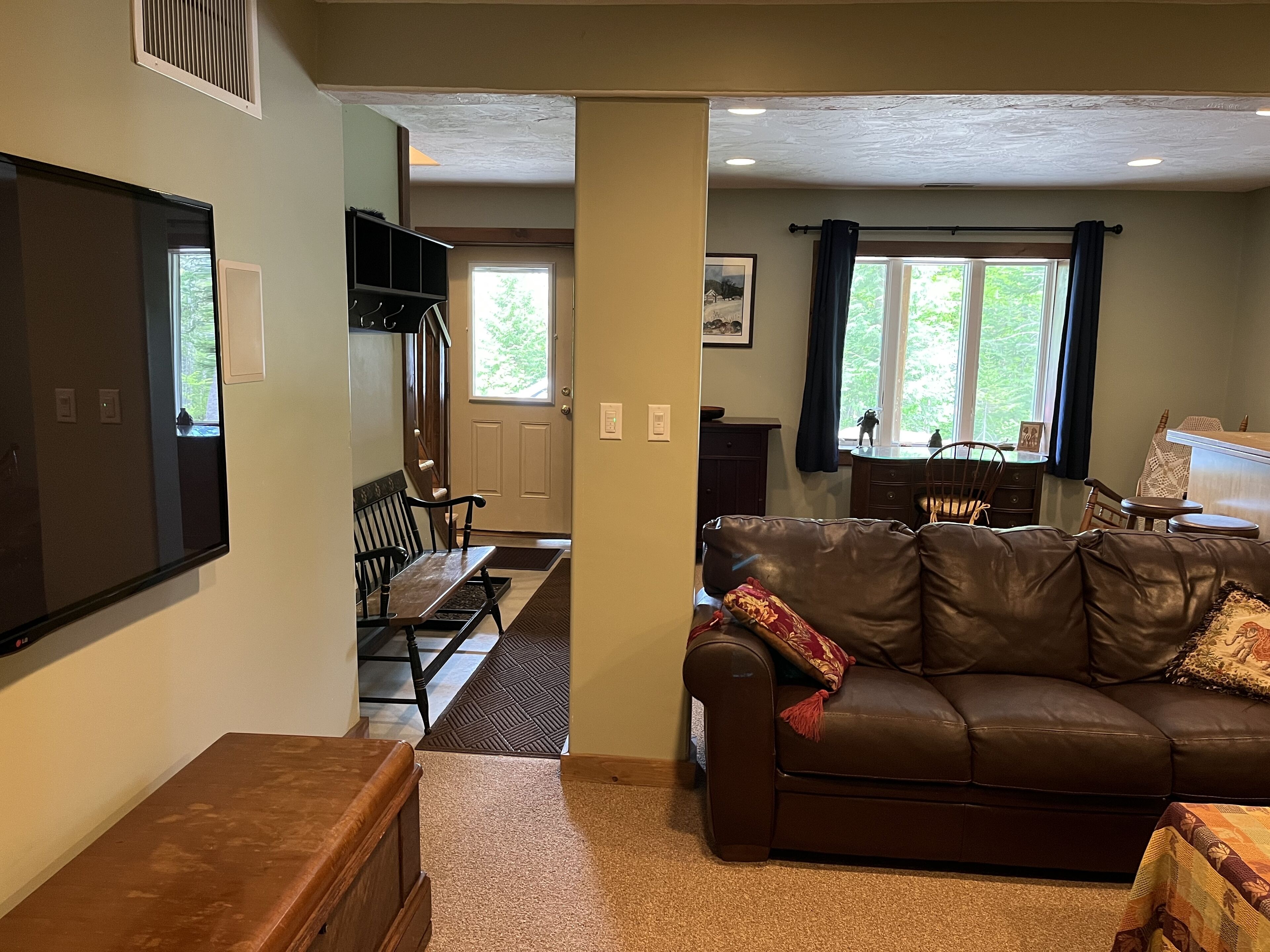 A living room with a brown leather sofa, a wooden coffee table, and a television mounted on the wall.