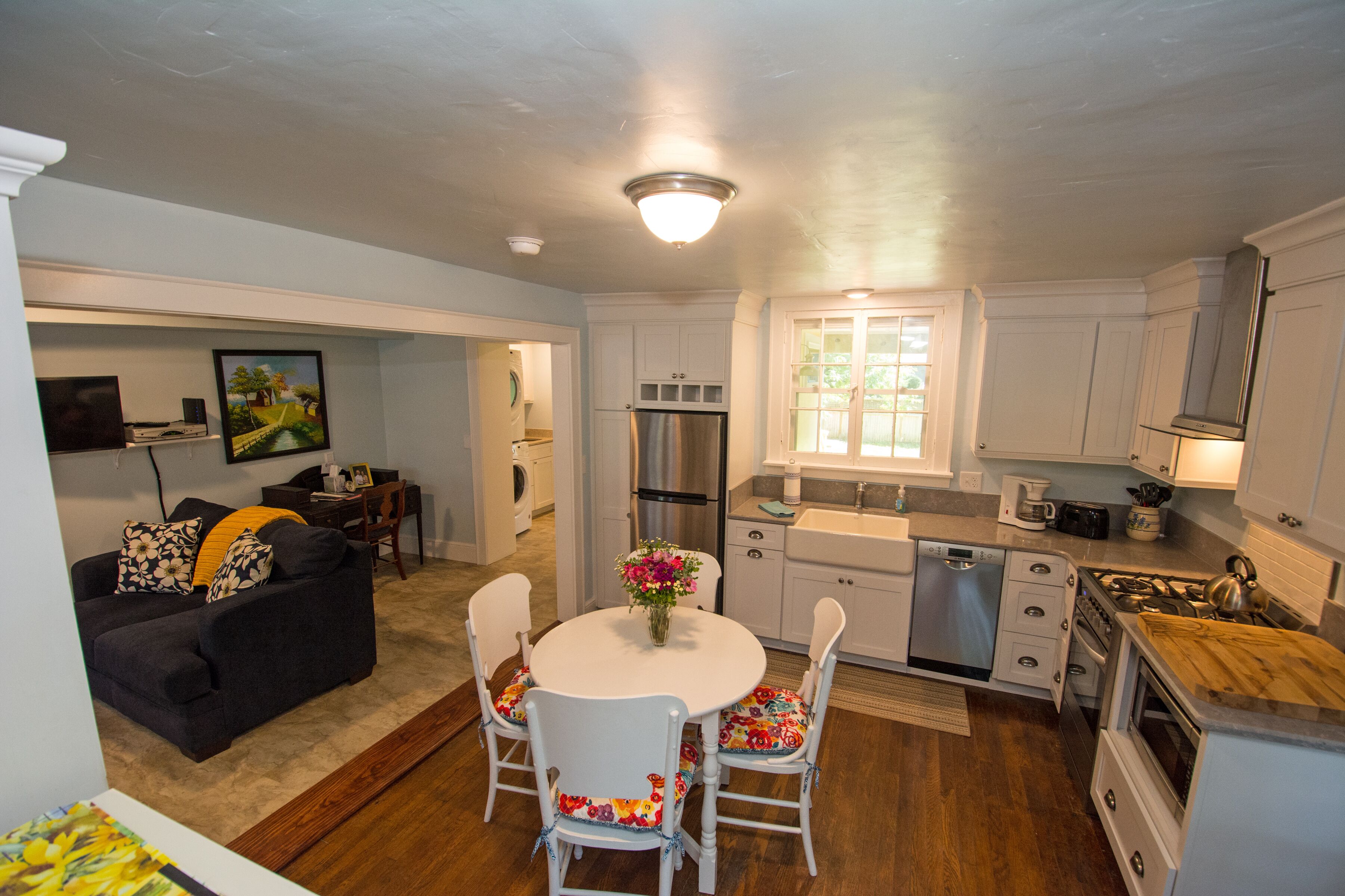 A compact kitchen with white cabinets, a stainless steel refrigerator, a built-in oven, and a wooden countertop.