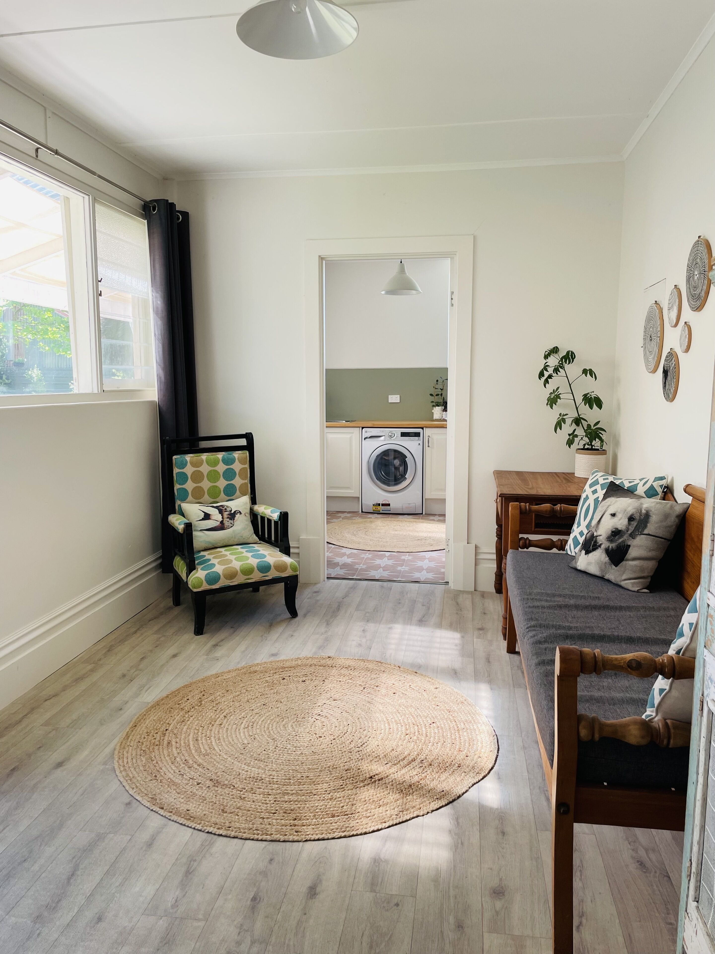A compact living space with a washing machine, a dining area, and a seating area with a round rug.