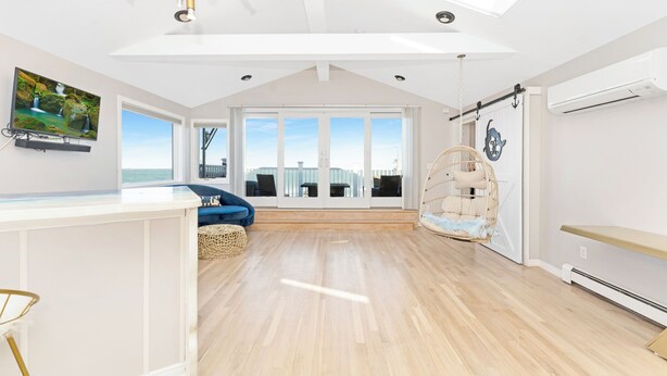 A spacious room with a large window, a ceiling fan, and a mounted TV.