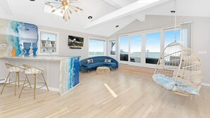 A spacious room with a large window, a hanging chair, a blue sofa, and a white ceiling with a star-shaped light fixture.