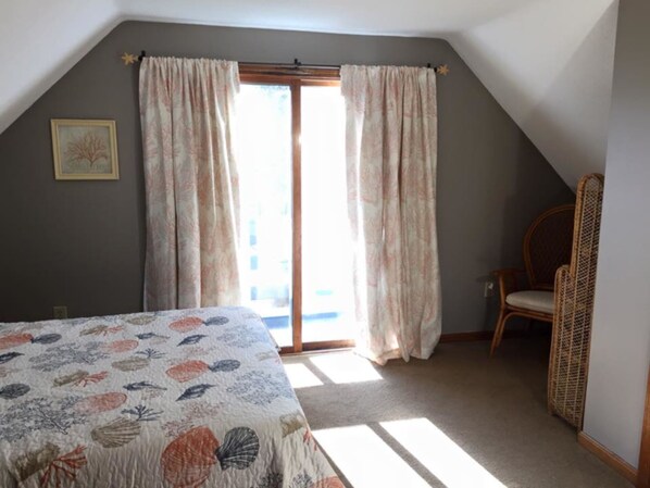 Un dormitorio con cama, una silla y ventana con cortinas.