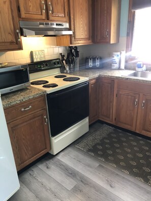 A kitchen with wooden cabinets, a microwave, a stove, and a toaster. - Year round beach house 5 minute walk to beach with all the comforts of home. (York)