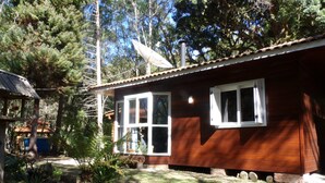 Una casa de madera con antena parabólica, una ventana y un pequeño jardín.