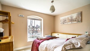 A bedroom with a bed, a window, a wooden dresser, and a painting on the wall. - 30 Woodsmill Quay - sleeps 3 guests  in 1 bedroom (York)