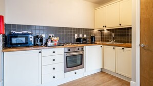 A kitchen with white cabinets, a microwave, a coffee maker, and a stove. - 30 Woodsmill Quay - sleeps 3 guests  in 1 bedroom (York)