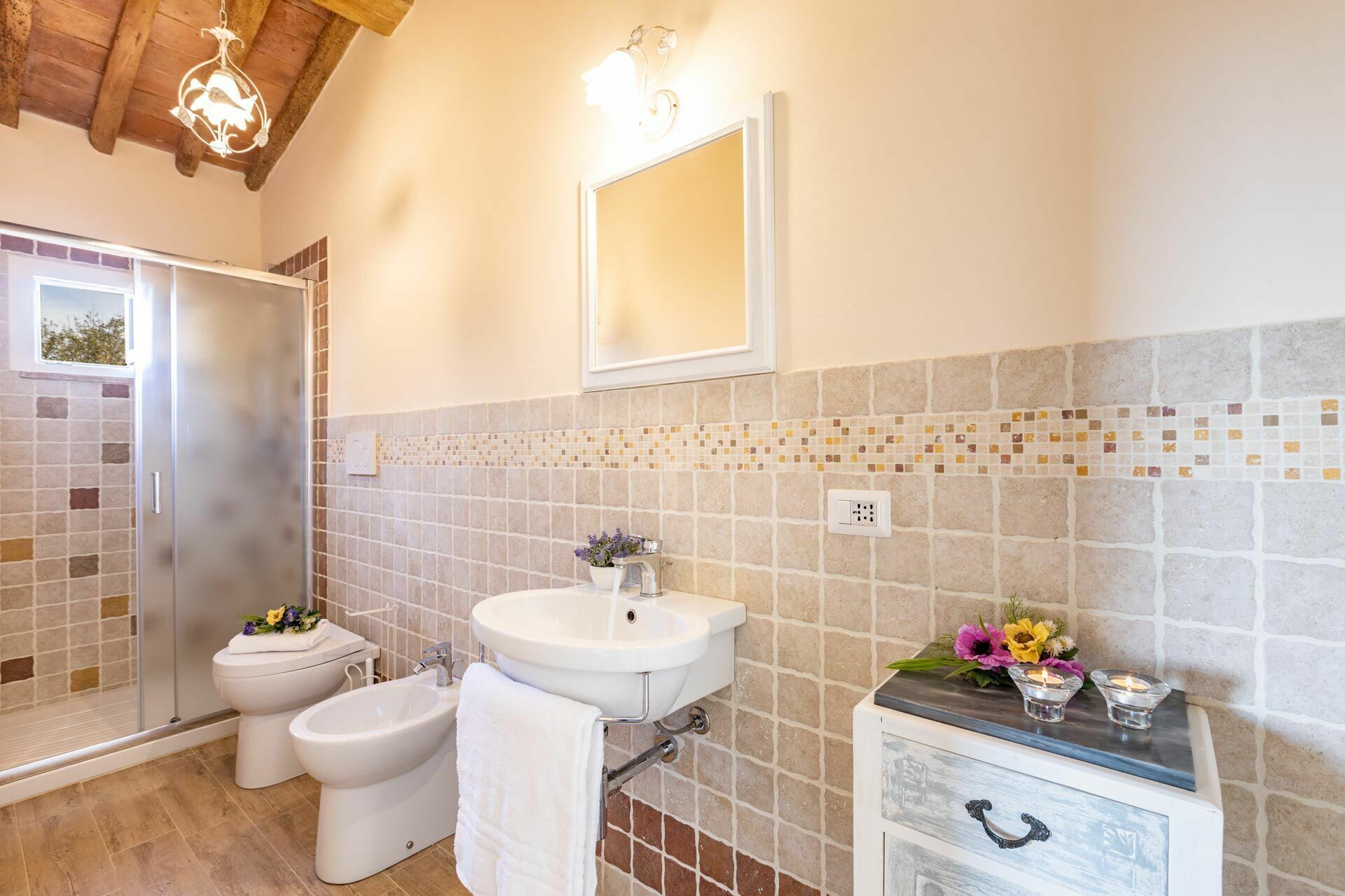 A bathroom with a shower, toilet, bidet, sink, and a mirror.