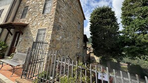 A stone building with a sloped roof, a gated entrance, and a bench outside.