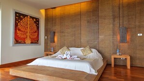 Amplia habitación con una cama grande, paneles de madera, un tapiz decorativo y dos mesitas de noche con botellas de agua.