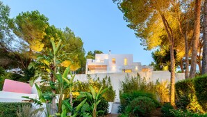A modern house with a white exterior, surrounded by lush greenery and trees. - Modern Luxury Villa,  - 10 mins to Cala Bassa - 15 mins to Jondal/Es Torrent (San Agustín)