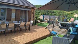 A patio area with outdoor seating, a wooden deck, and a view of a hilly landscape. - Riverfront house with swimming pool and magnificent view of the mountains and cliffs. (Trèves)