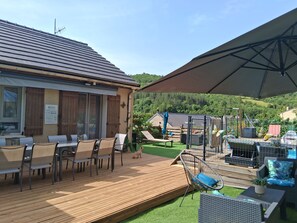 A patio area with outdoor seating, a wooden deck, and a view of a hilly landscape. - Riverfront house with swimming pool and magnificent view of the mountains and cliffs. (Trèves)